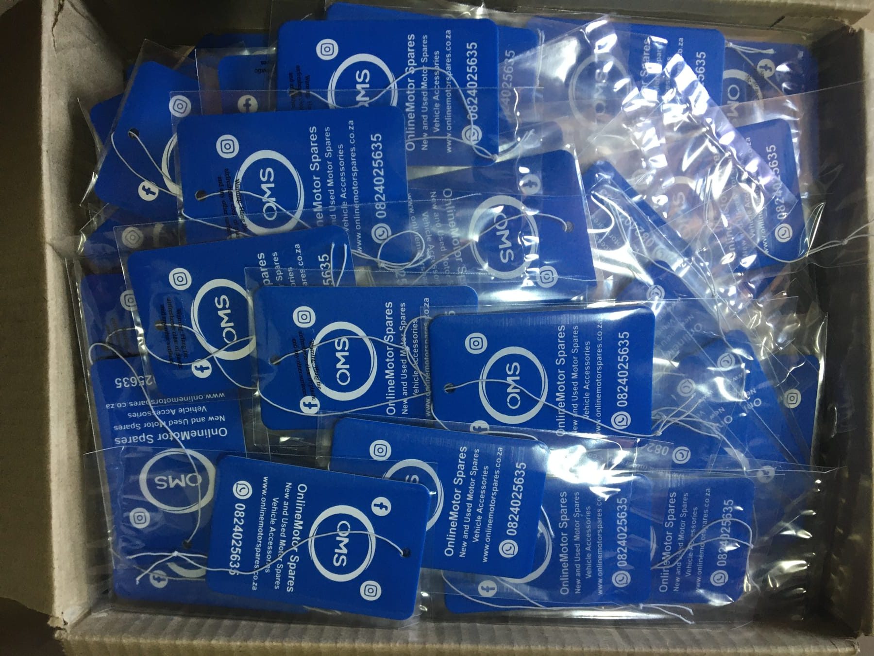 Box of custom car air fresheners printed for Online Motor Spares, individually packaged